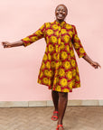 Model wearing red dress with yellow and brown flowers.