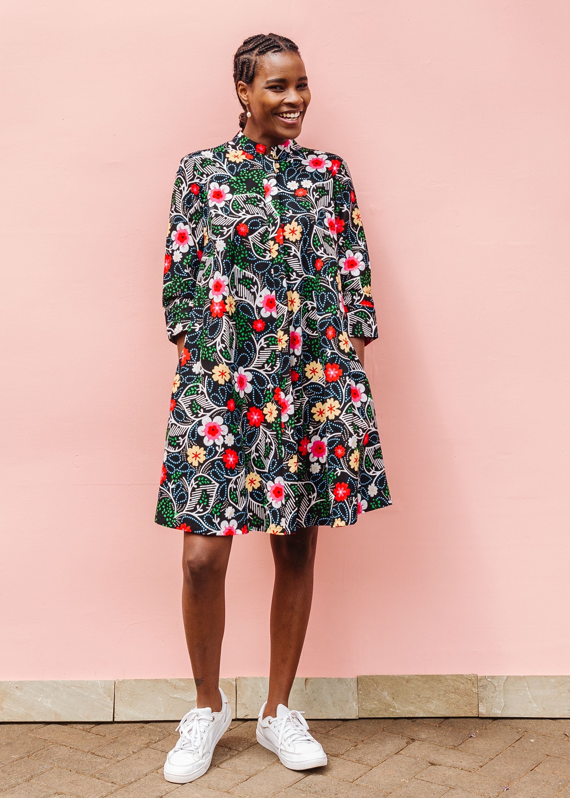 Model wearing black dress with white, green, red and yellow floral print.