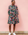 Model wearing black dress with white, green, red and yellow floral print.