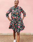 Model wearing black dress with white, green, red and yellow floral print.