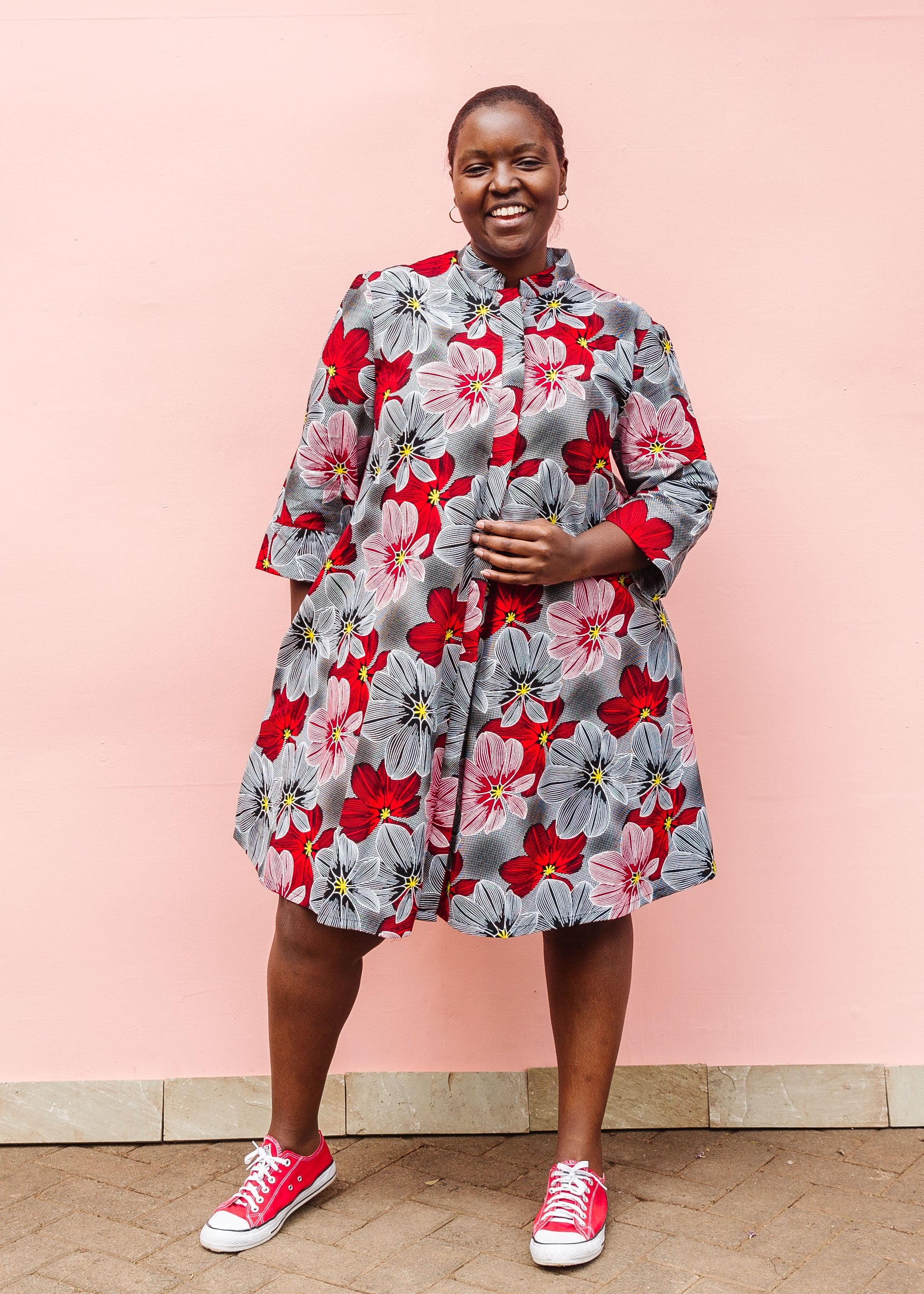 Model wearing dress with large grey and red flower print.
