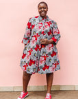 Model wearing dress with large grey and red flower print.