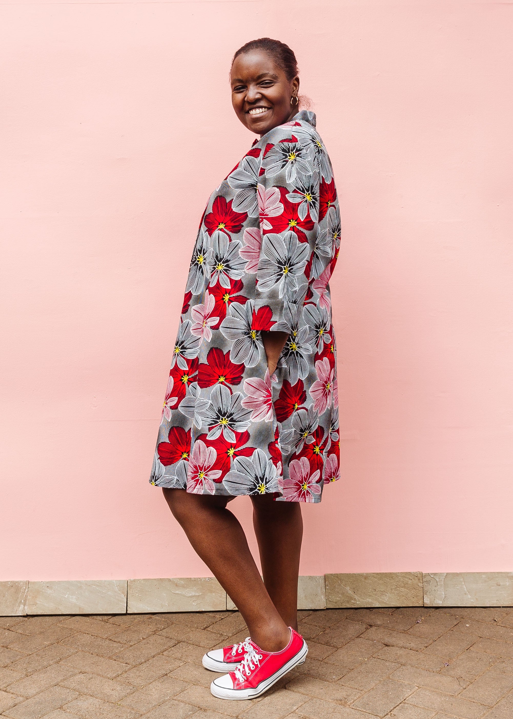 Model wearing dress with large grey and red flower print.