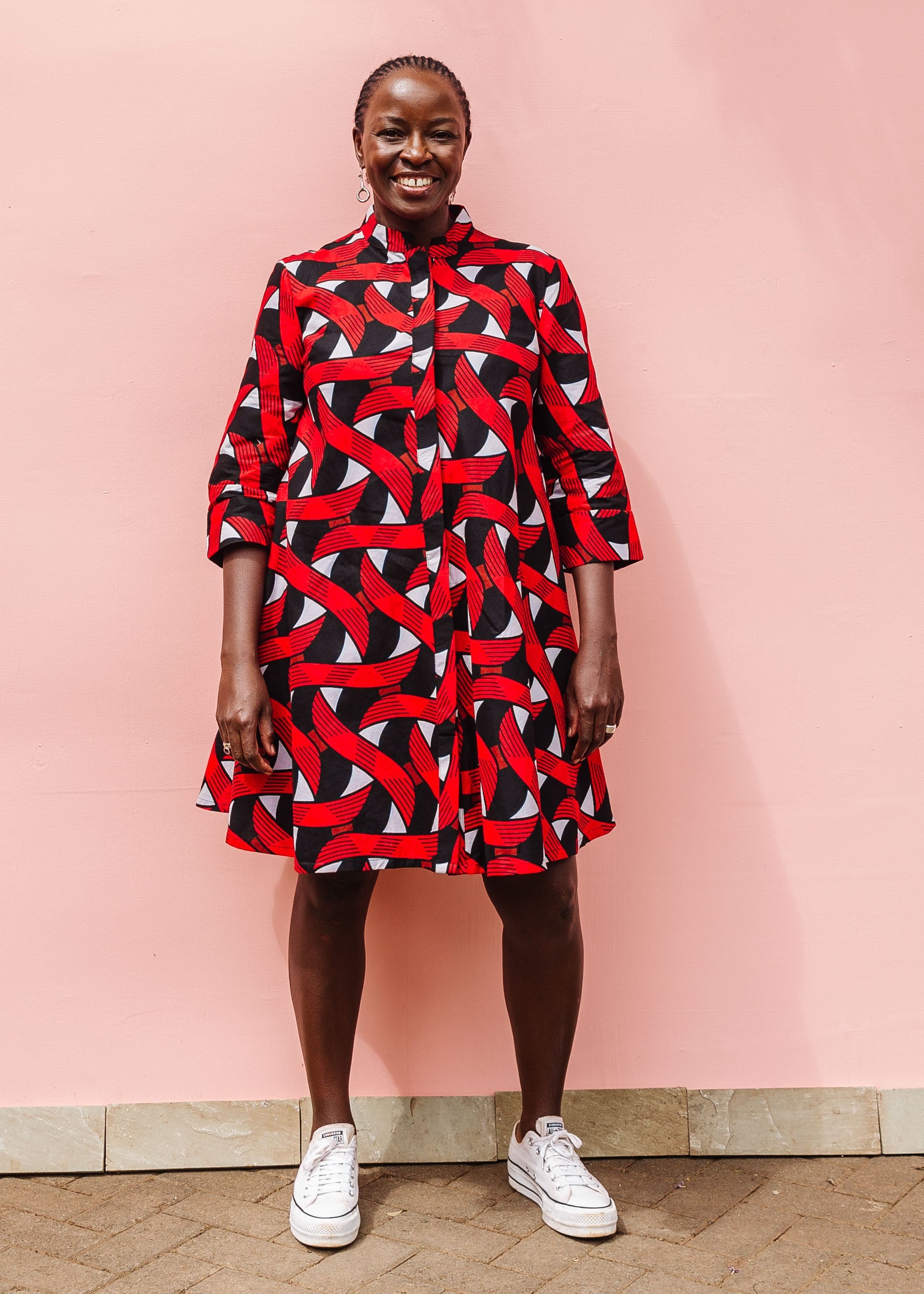 Model wearing red, black and white ribbon print dress.