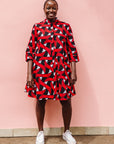 Model wearing red, black and white ribbon print dress.