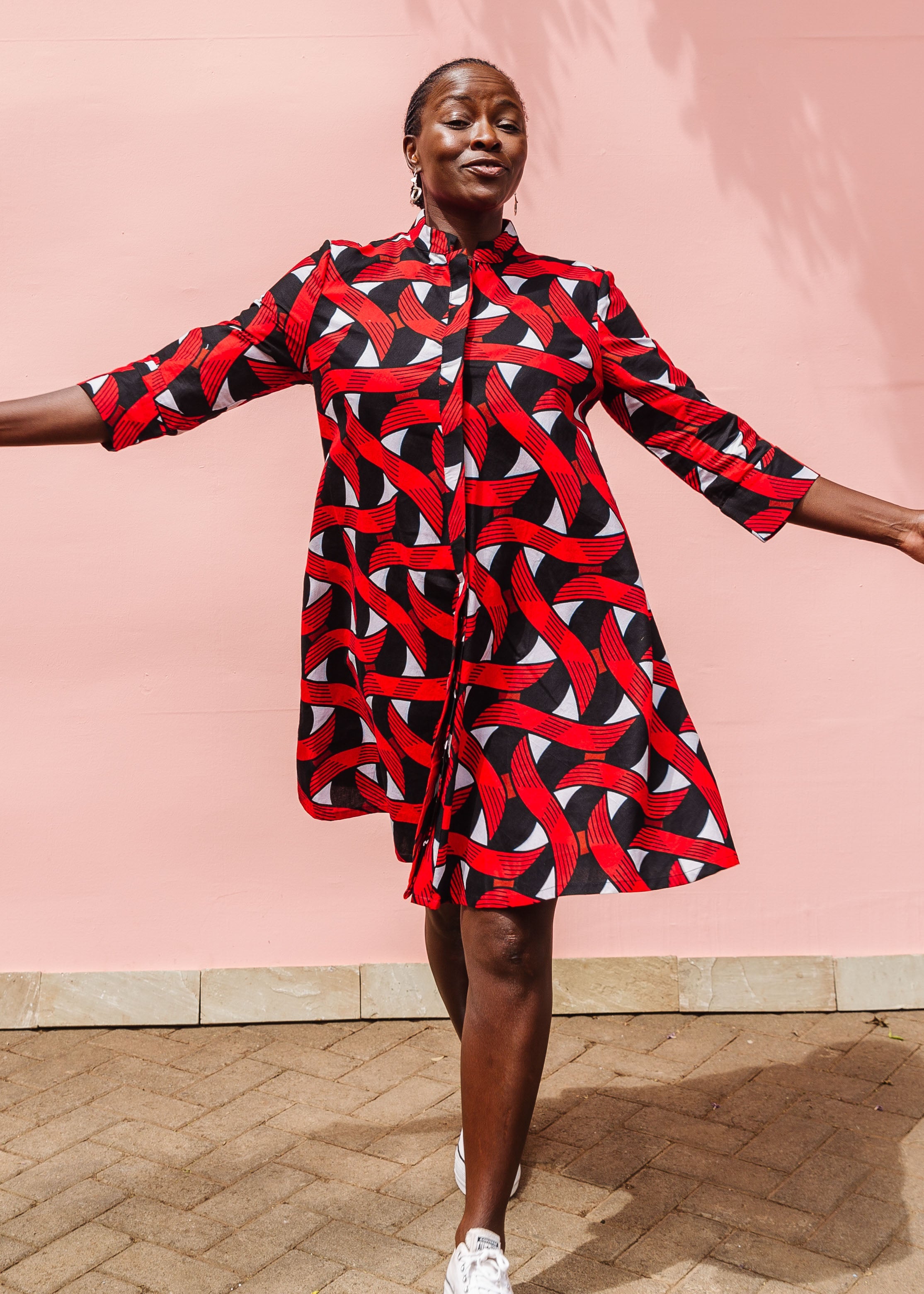 Model wearing red, black and white ribbon print dress.