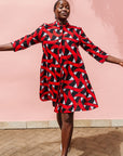 Model wearing red, black and white ribbon print dress.