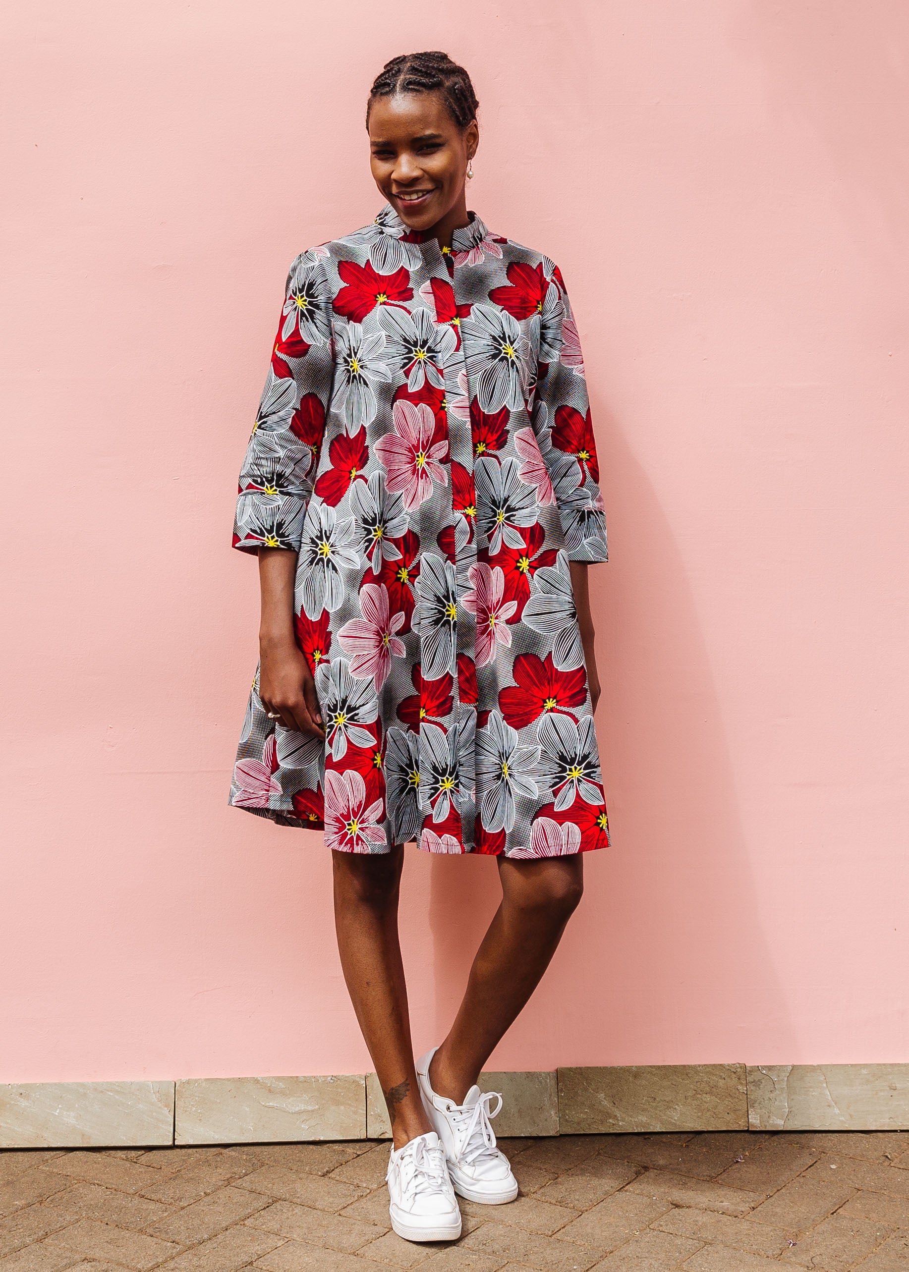 Model wearing dress with large grey and red flower print.