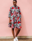Model wearing dress with large grey and red flower print.