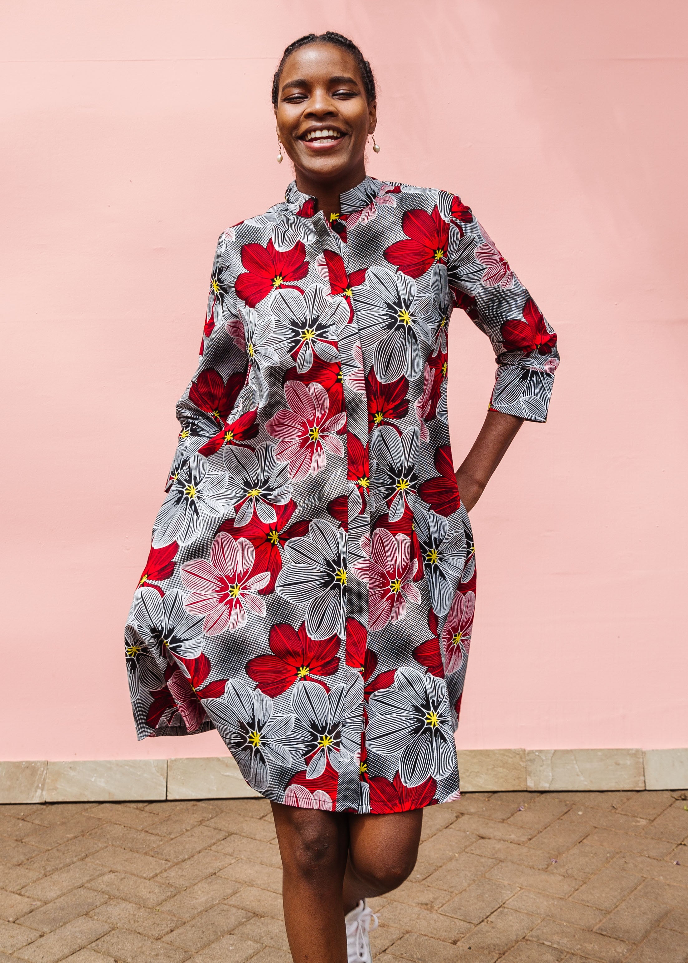 Model wearing dress with large grey and red flower print.