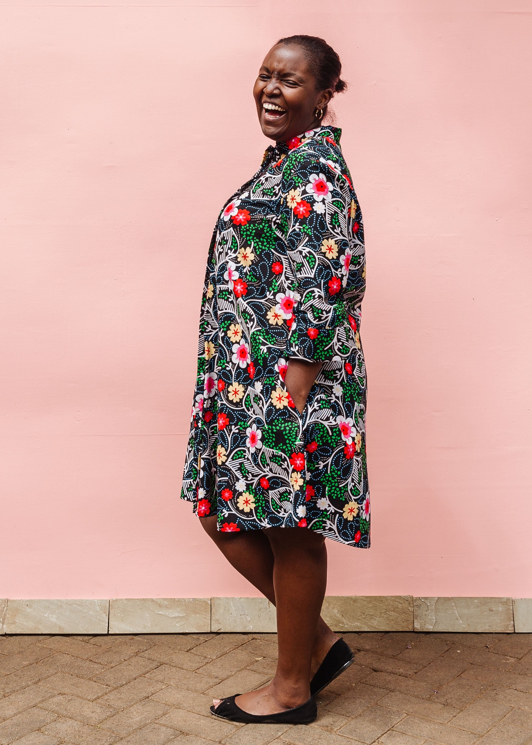 Model wearing black dress with white, green, red and yellow floral print.