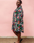 Model wearing black dress with white, green, red and yellow floral print.