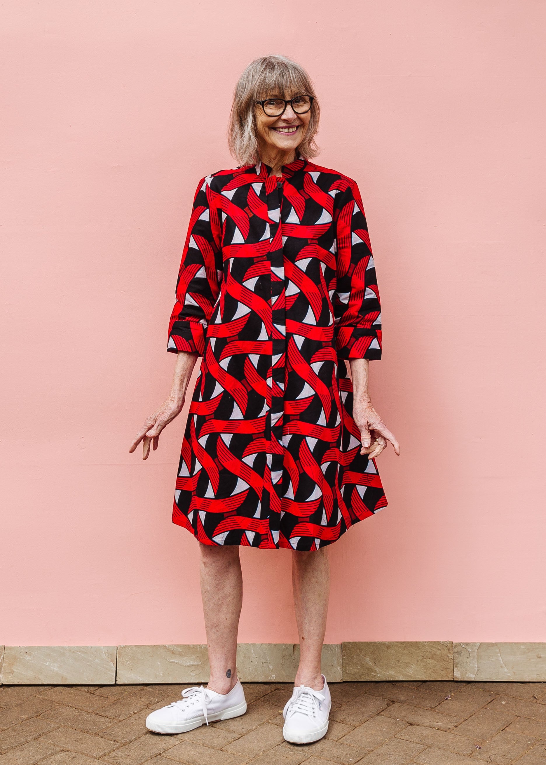 Model wearing red, black and white ribbon print dress.