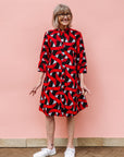 Model wearing red, black and white ribbon print dress.