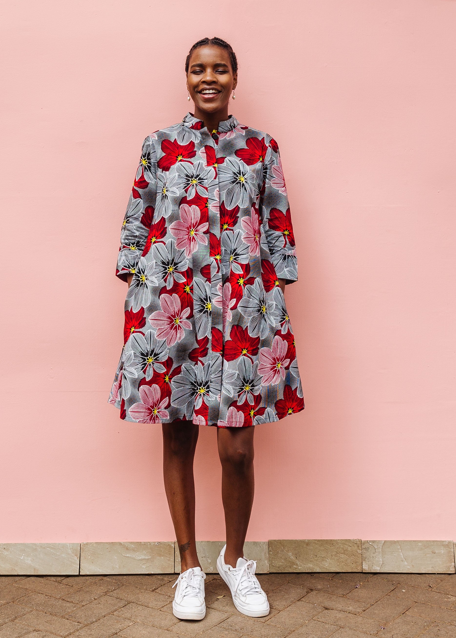 Model wearing dress with large grey and red flower print.