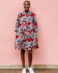 Model wearing dress with large grey and red flower print.