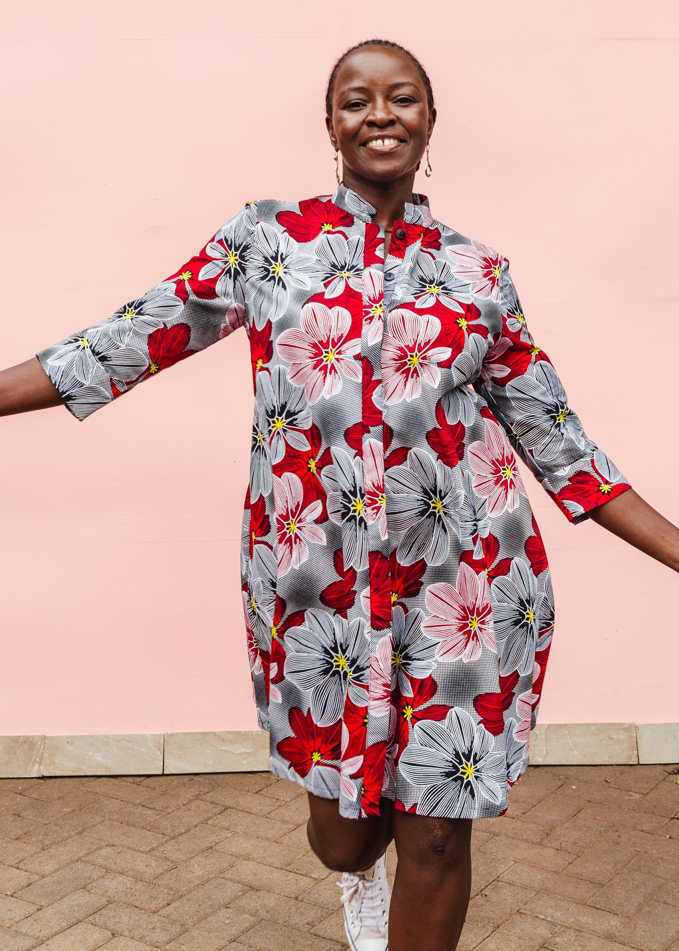 Model wearing dress with large grey and red flower print.