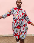 Model wearing dress with large grey and red flower print.