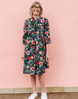 Model wearing black dress with white, green, red and yellow floral print.