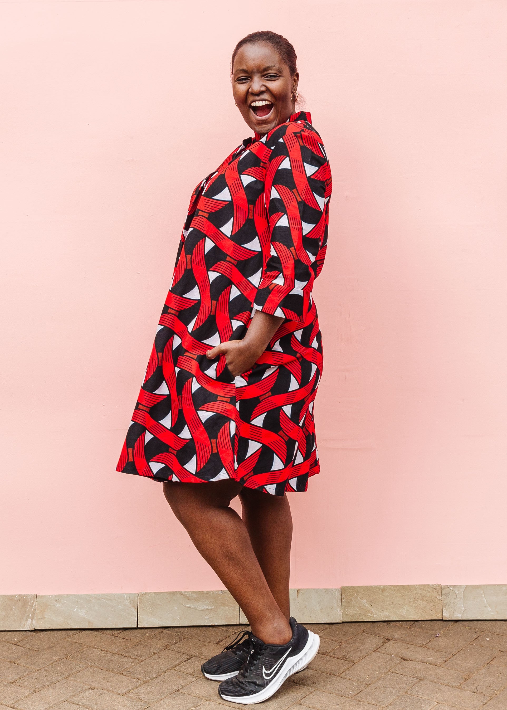Model wearing red, black and white ribbon print dress.