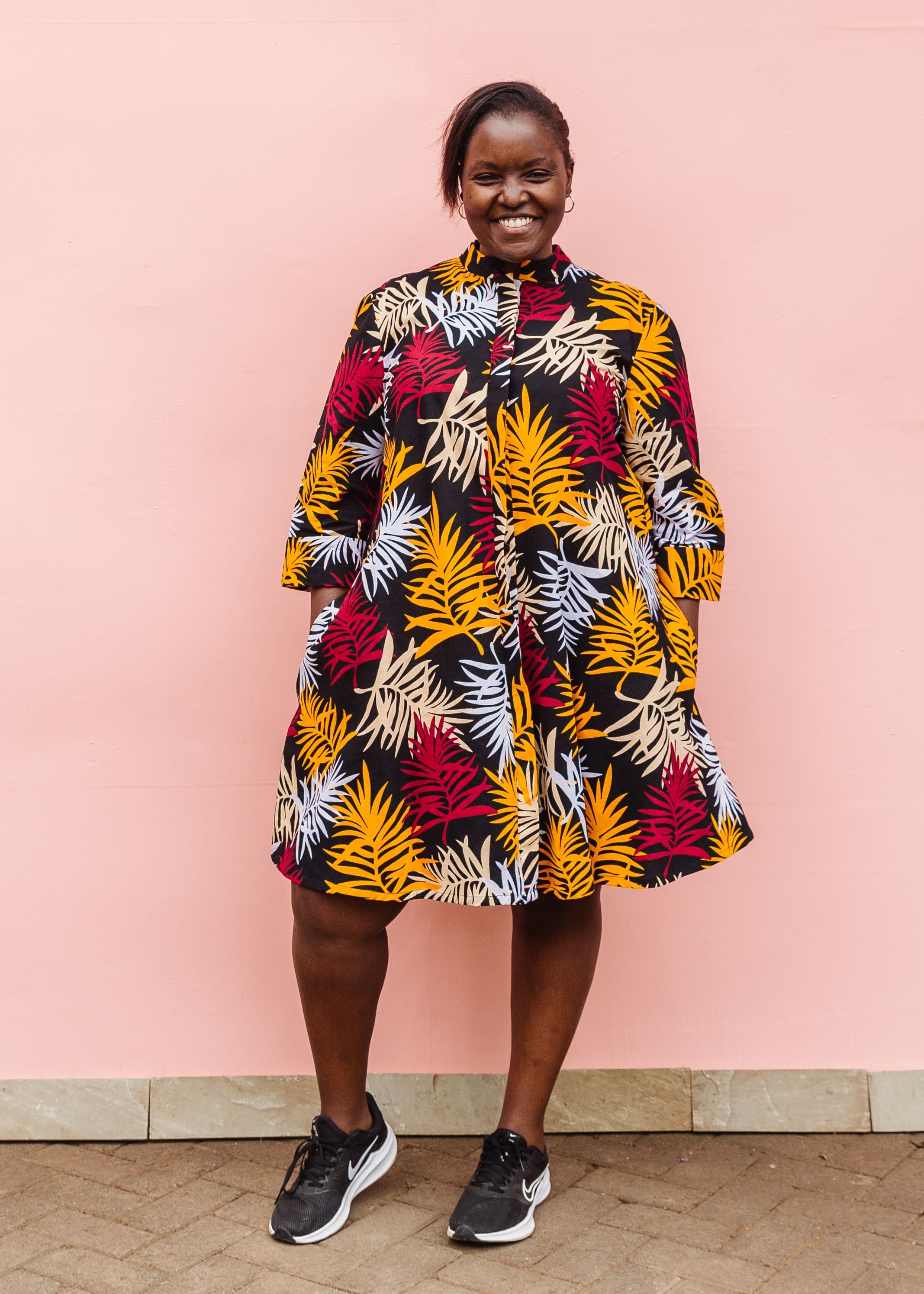 Model wearing black dress with orange, red and white leaf print.