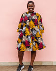 Model wearing black dress with orange, red and white leaf print.