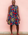 Model wearing navy sleeveless dress with red, yellow and white splatter print.