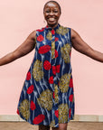 Model wearing navy sleeveless dress with red, yellow and white splatter print.