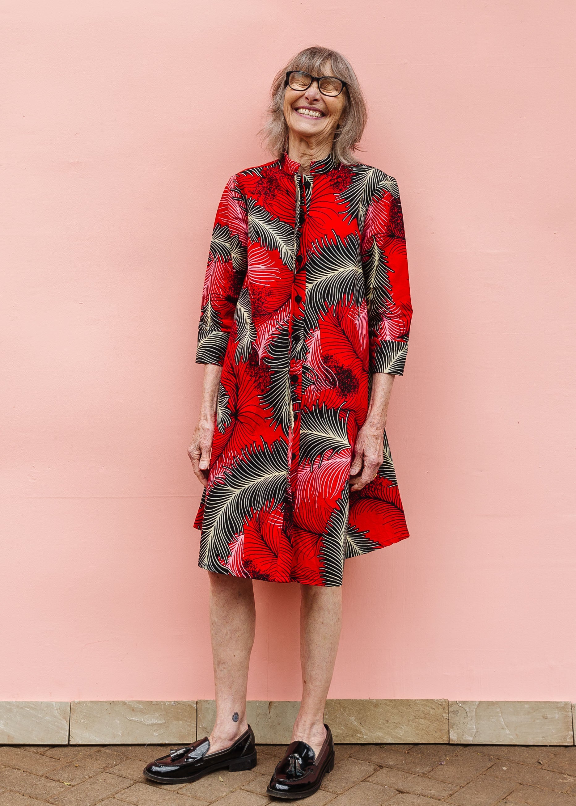Model wearing red dress with black and white feather print.