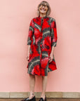 Model wearing red dress with black and white feather print.