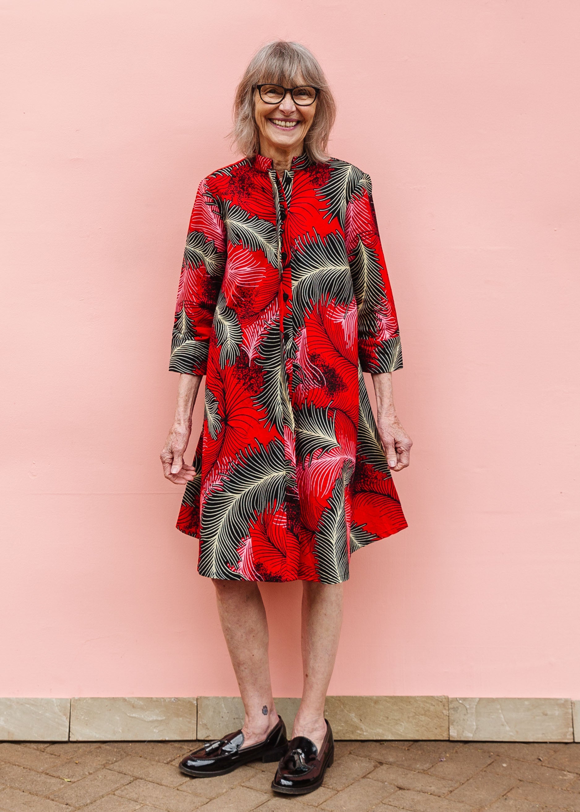 Model wearing red dress with black and white feather print.
