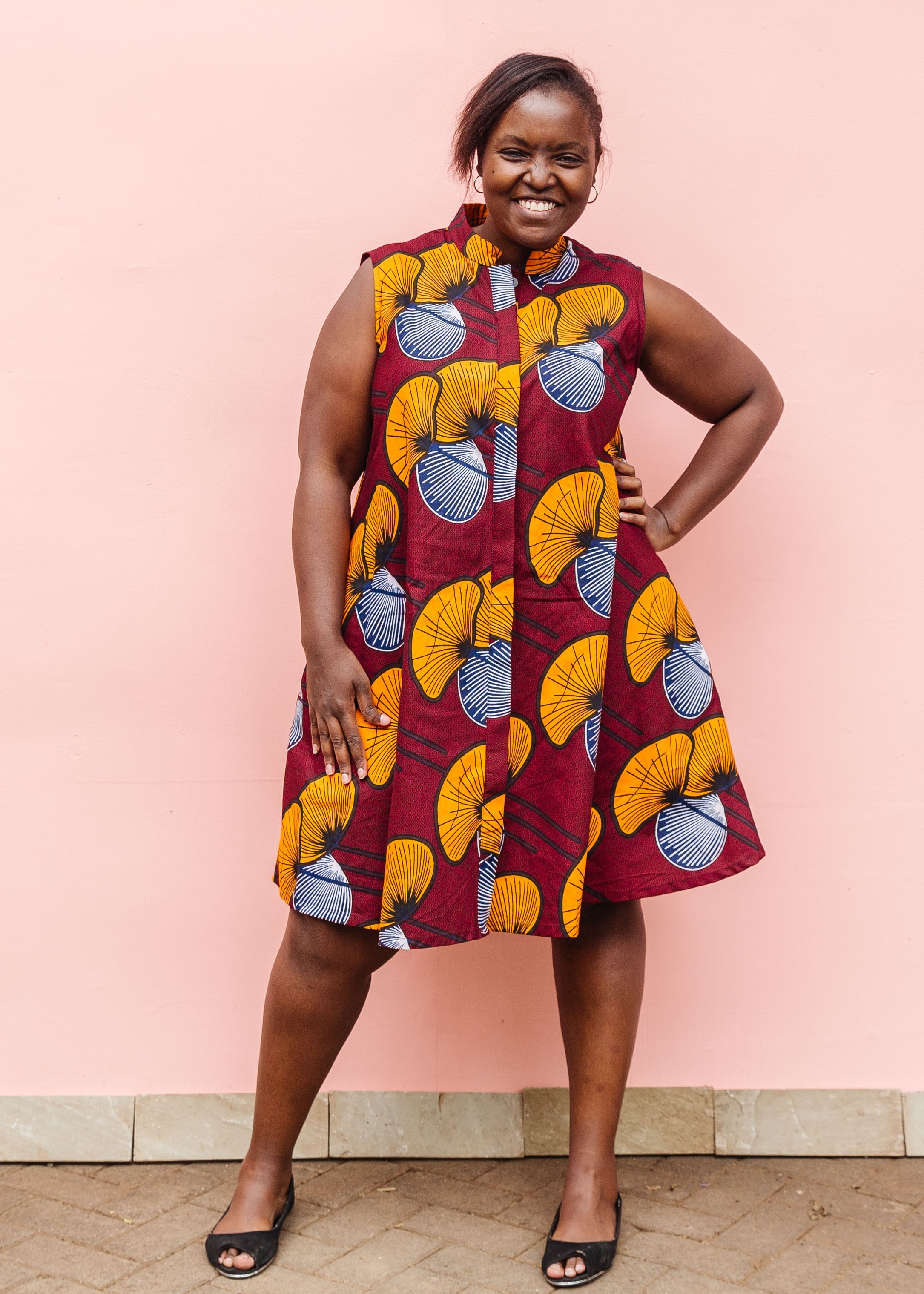 Model wearing burgundy sleeveless dress with yellow and white flowers.