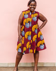 Model wearing burgundy sleeveless dress with yellow and white flowers.