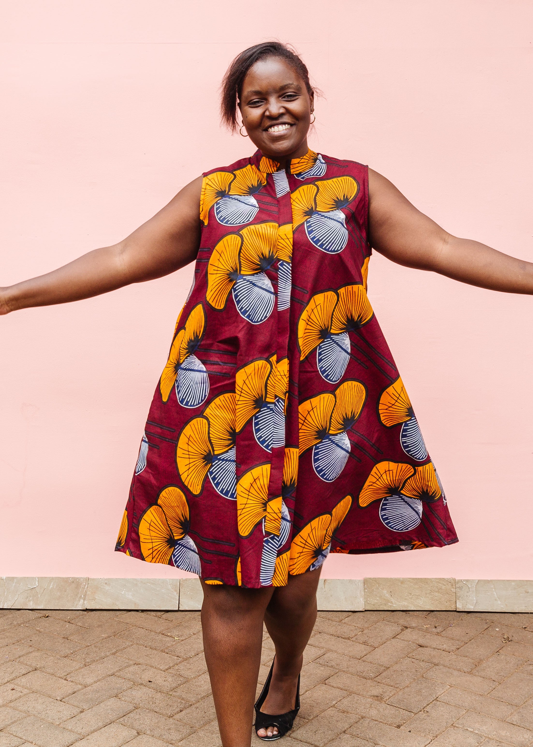 Model wearing burgundy sleeveless dress with yellow and white flowers.