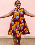 Model wearing burgundy sleeveless dress with yellow and white flowers.