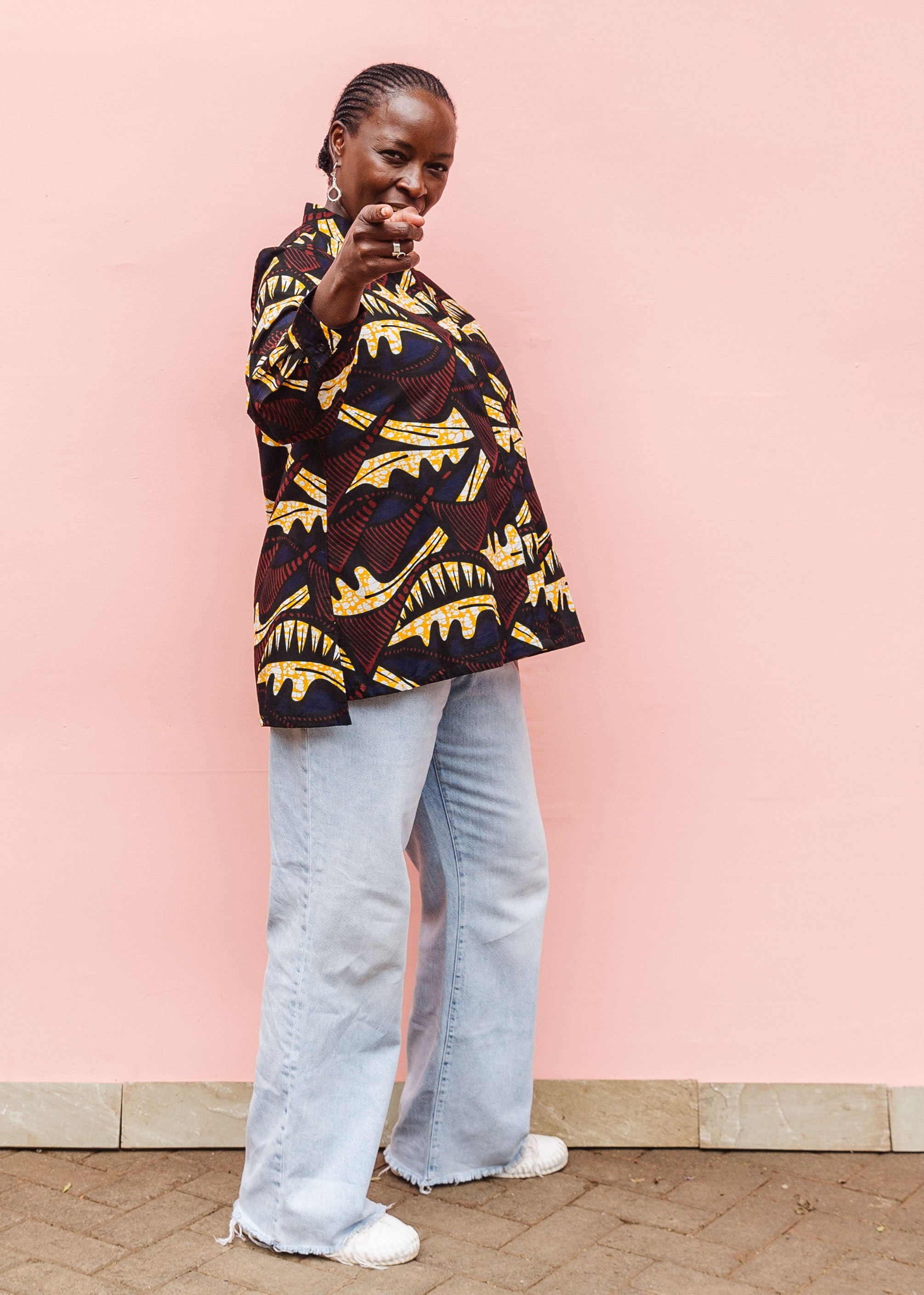 Model wearing long sleeve blouse with brown and yellow abstract print.