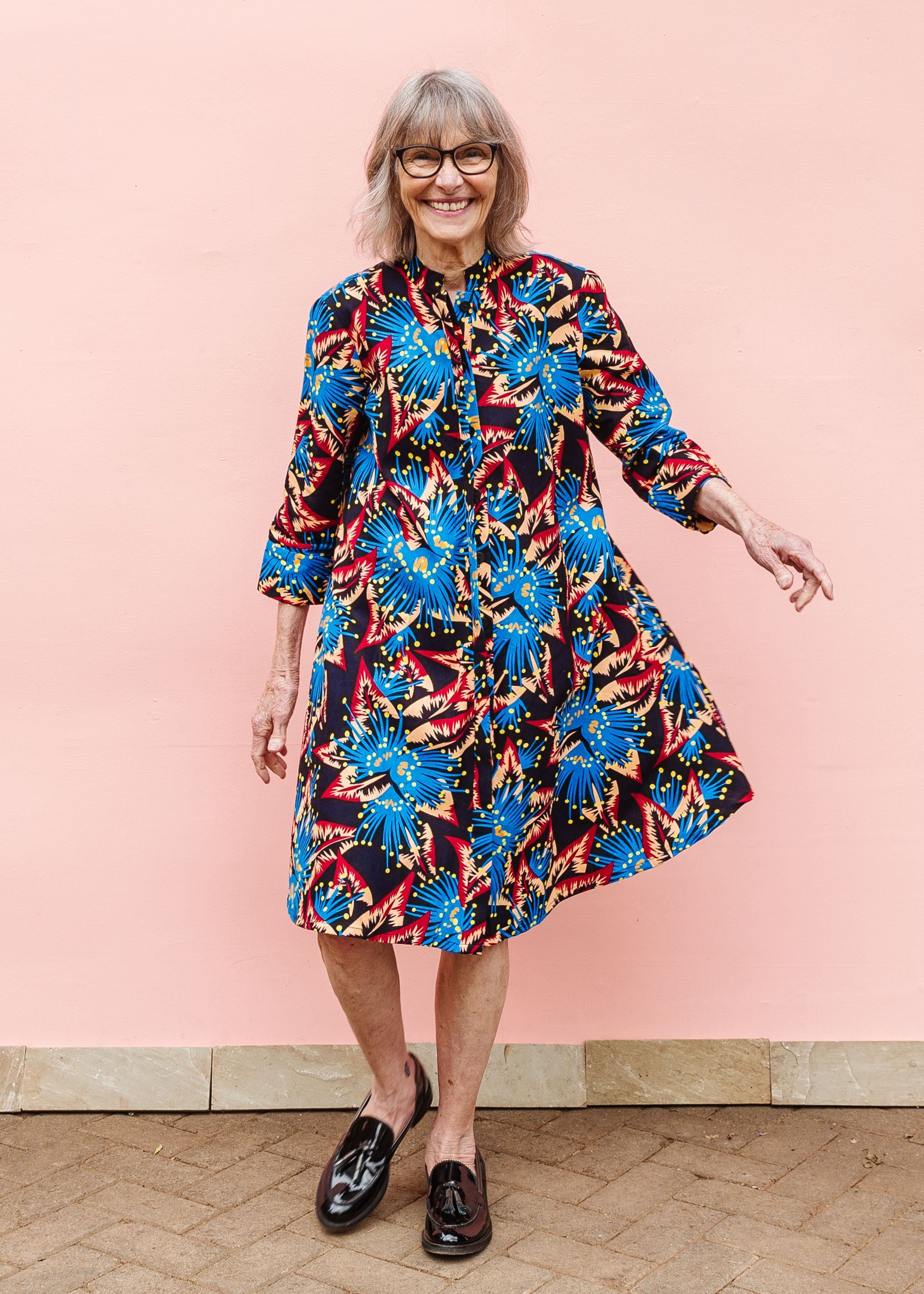 Model wearing black dress with blue, beige and red splatter print.