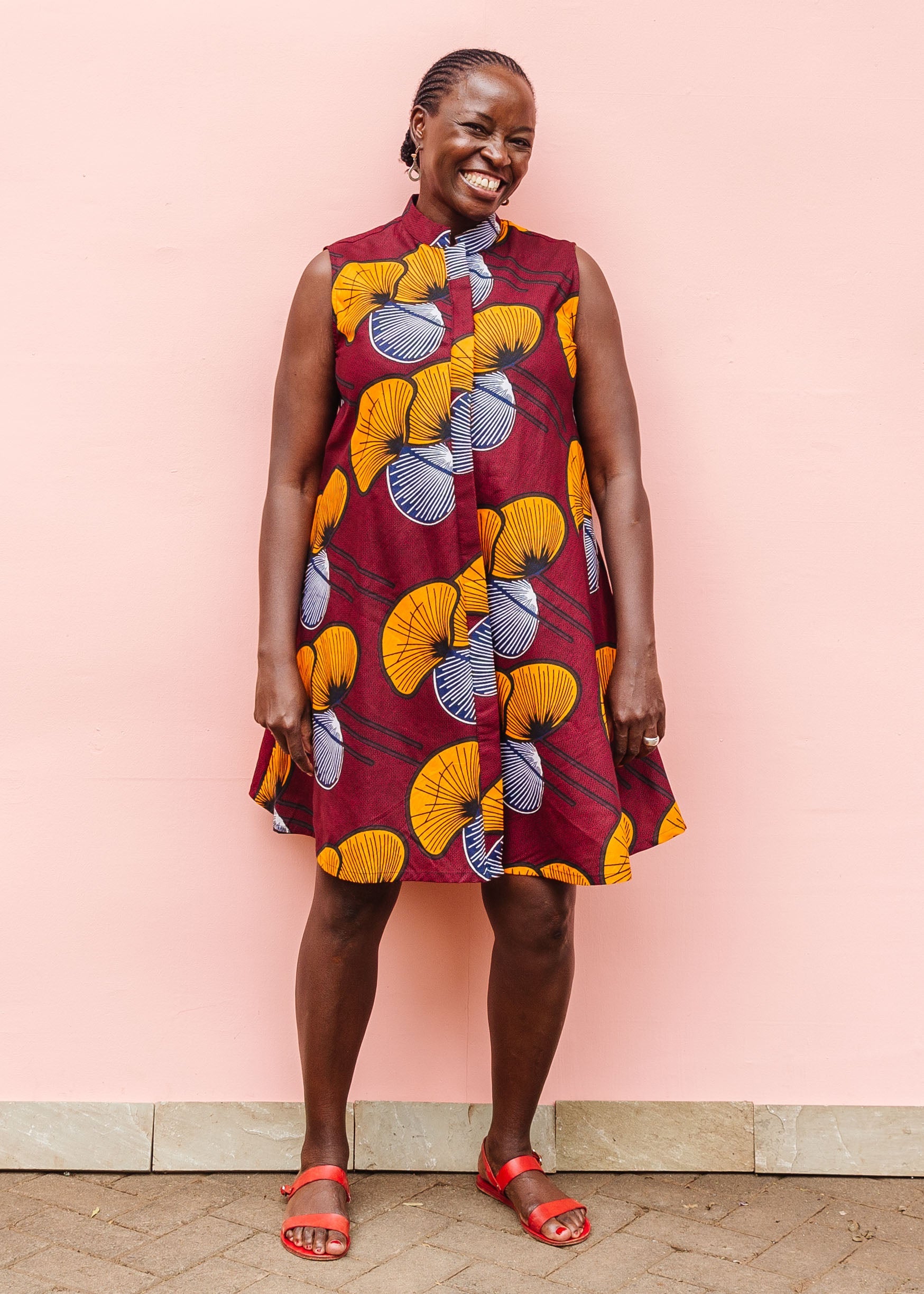 Model wearing burgundy sleeveless dress with yellow and white flowers.