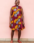 Model wearing burgundy sleeveless dress with yellow and white flowers.
