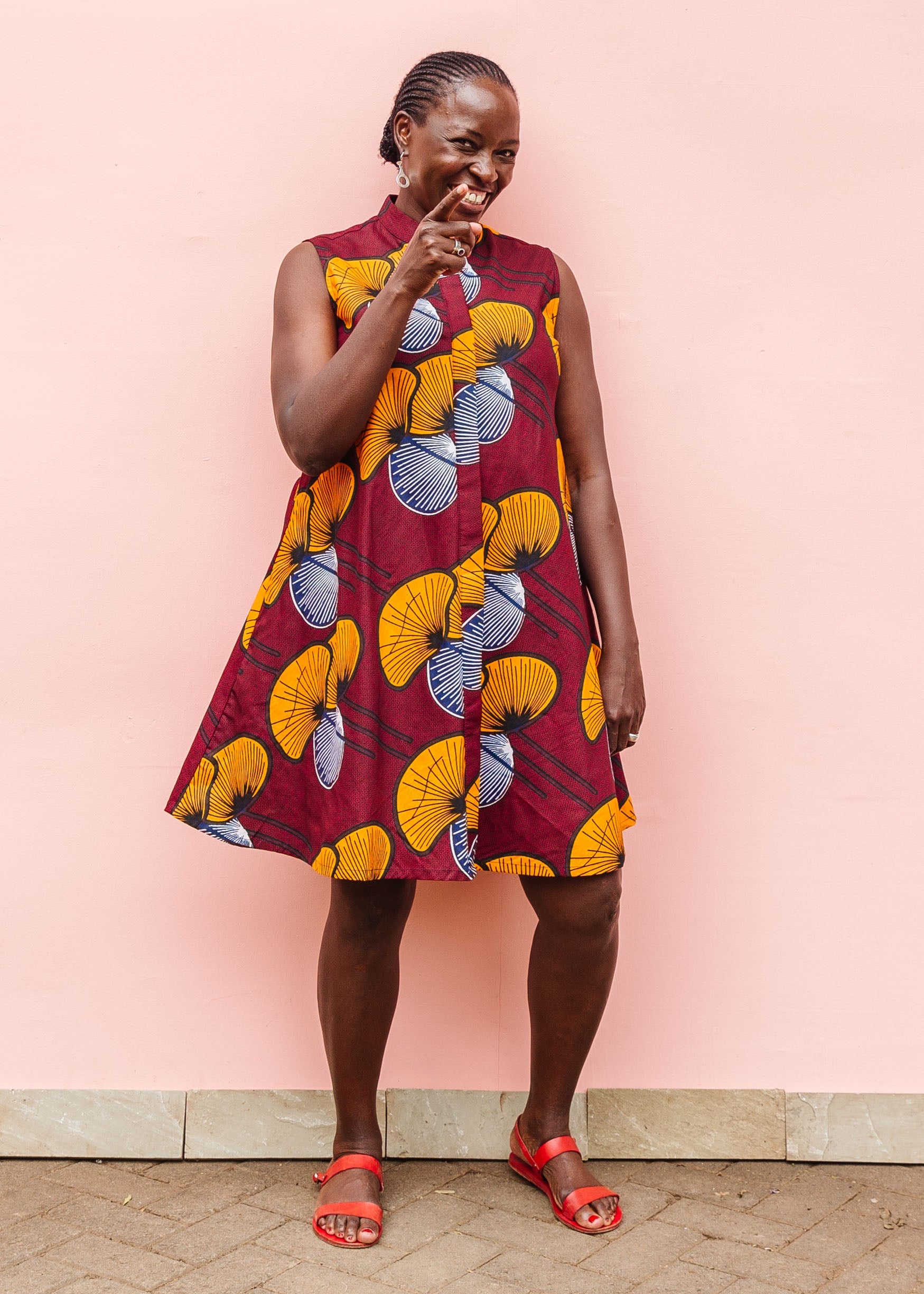 Model wearing burgundy sleeveless dress with yellow and white flowers.