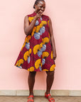 Model wearing burgundy sleeveless dress with yellow and white flowers.