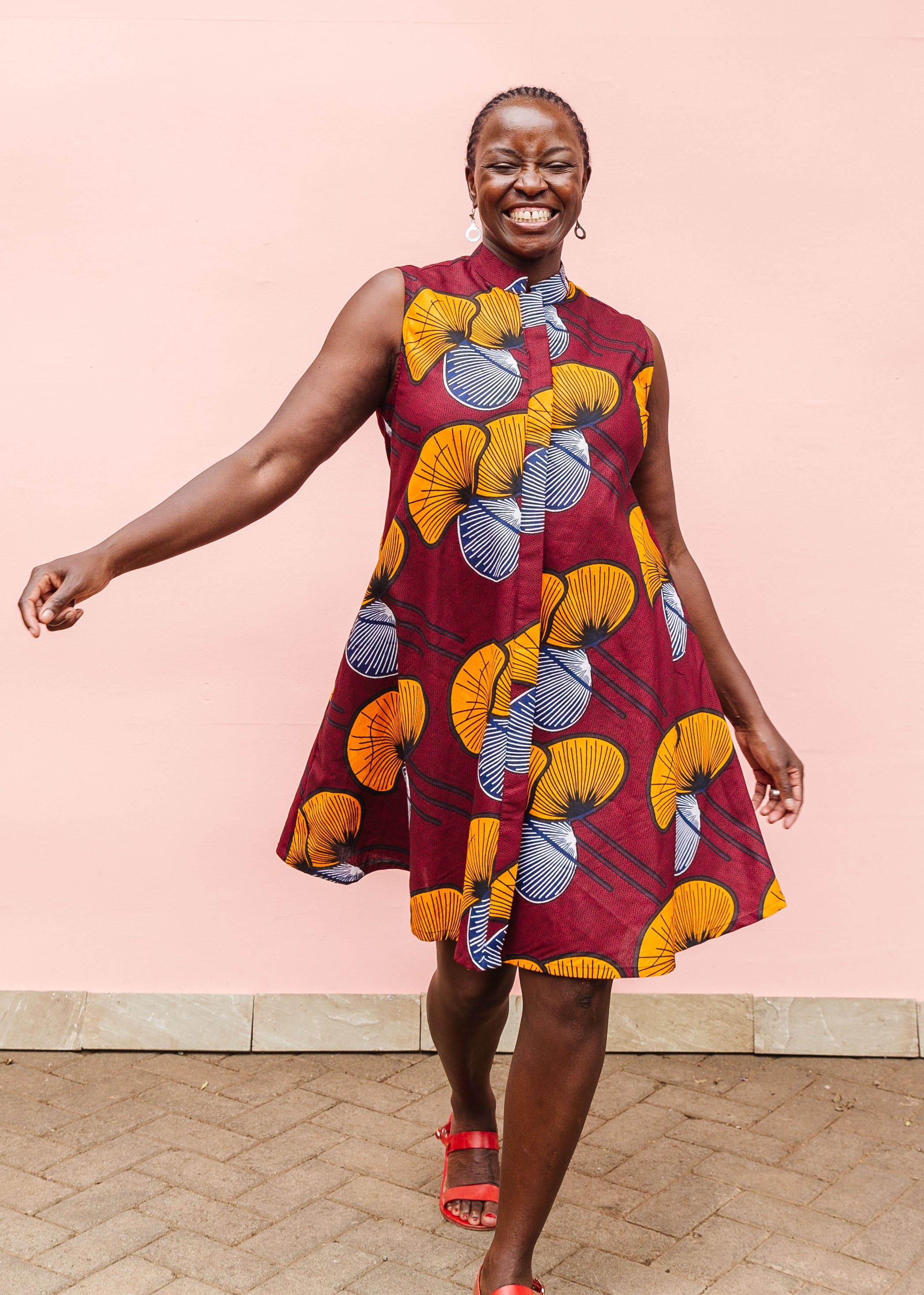 Model wearing burgundy sleeveless dress with yellow and white flowers.