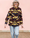 Model wearing long sleeve blouse with brown and yellow abstract print.