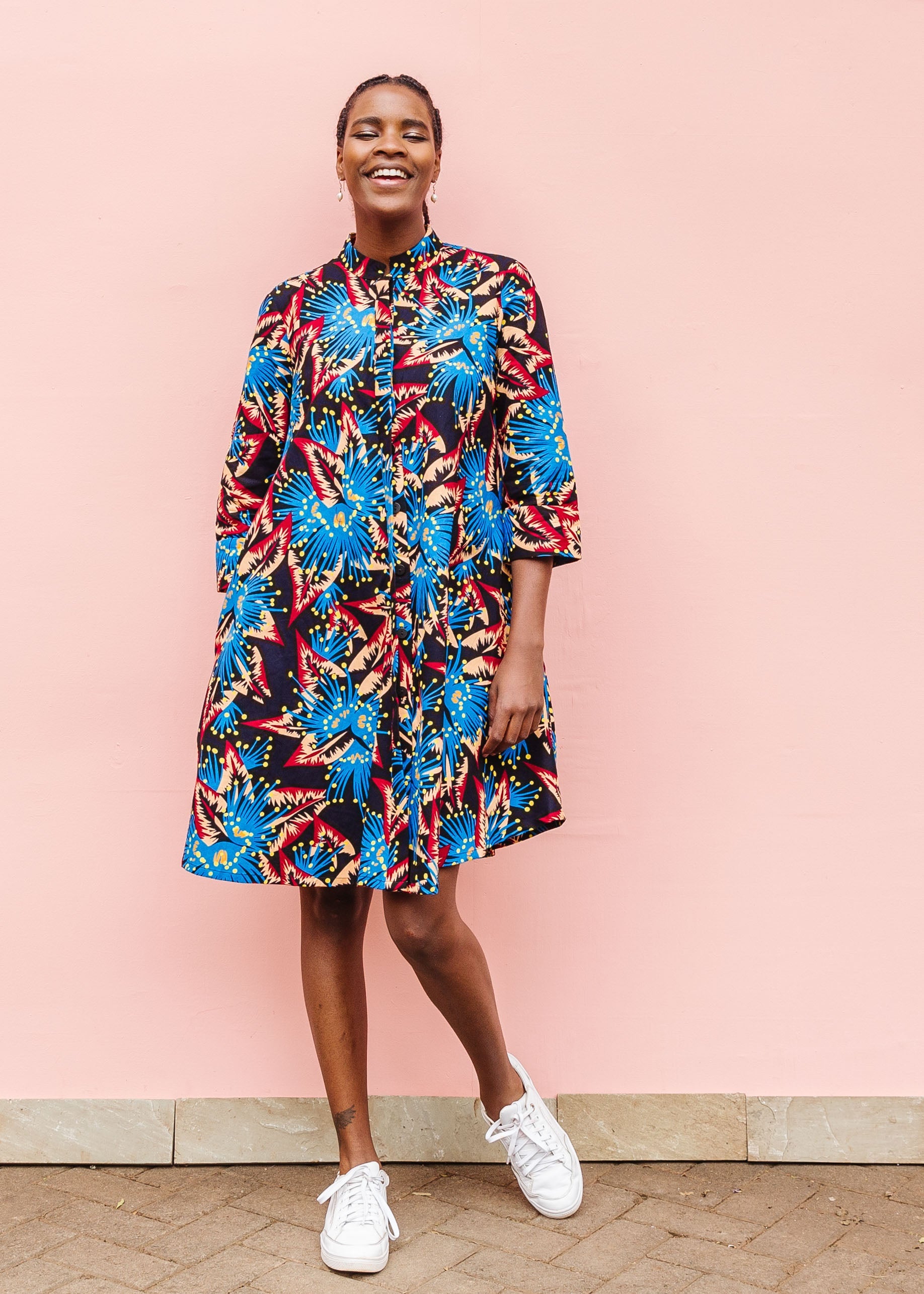 Model wearing black dress with blue, beige and red splatter print.