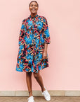 Model wearing black dress with blue, beige and red splatter print.
