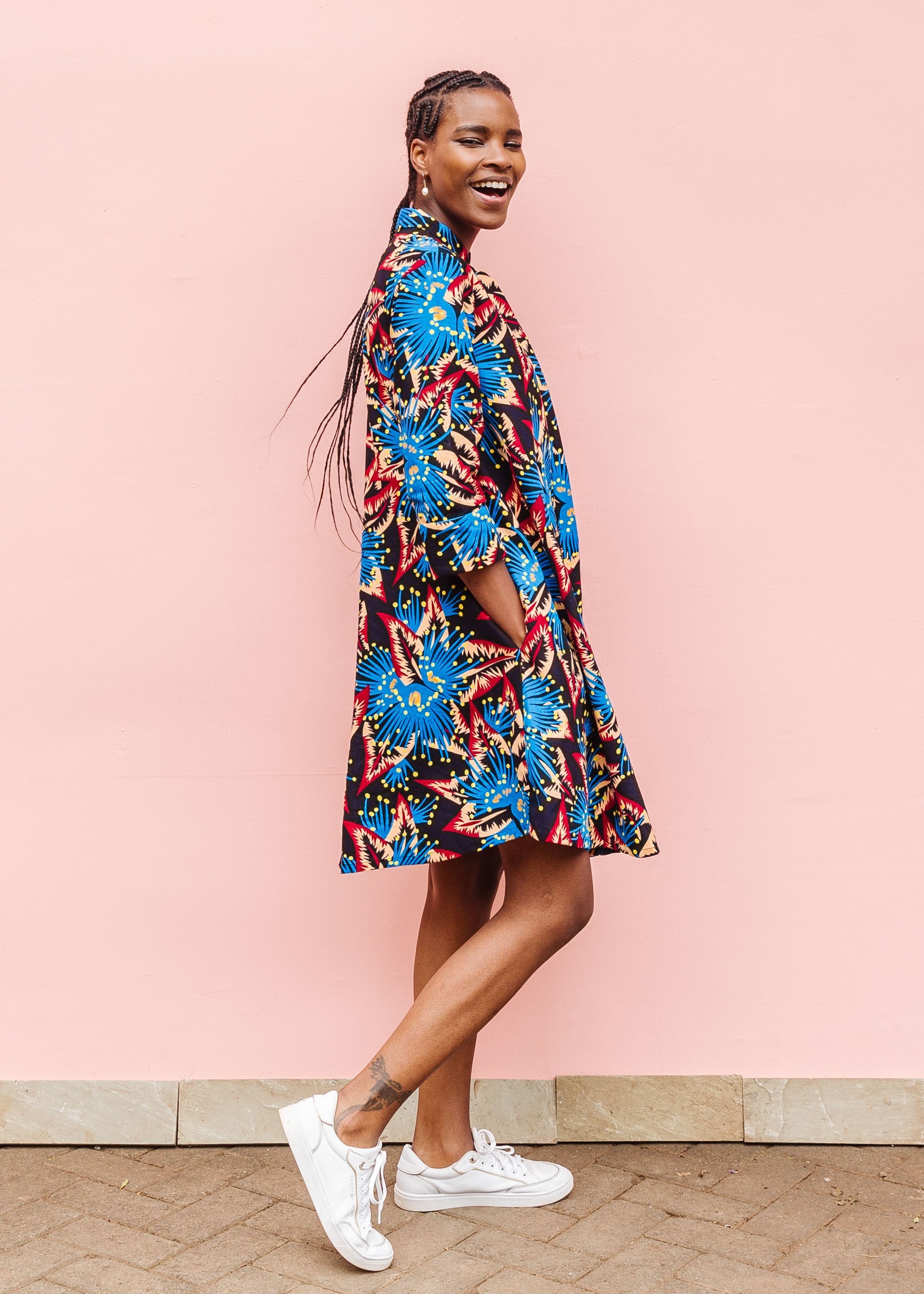Model wearing black dress with blue, beige and red splatter print.