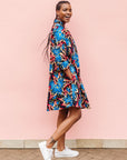 Model wearing black dress with blue, beige and red splatter print.