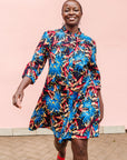 Model wearing black dress with blue, beige and red splatter print.