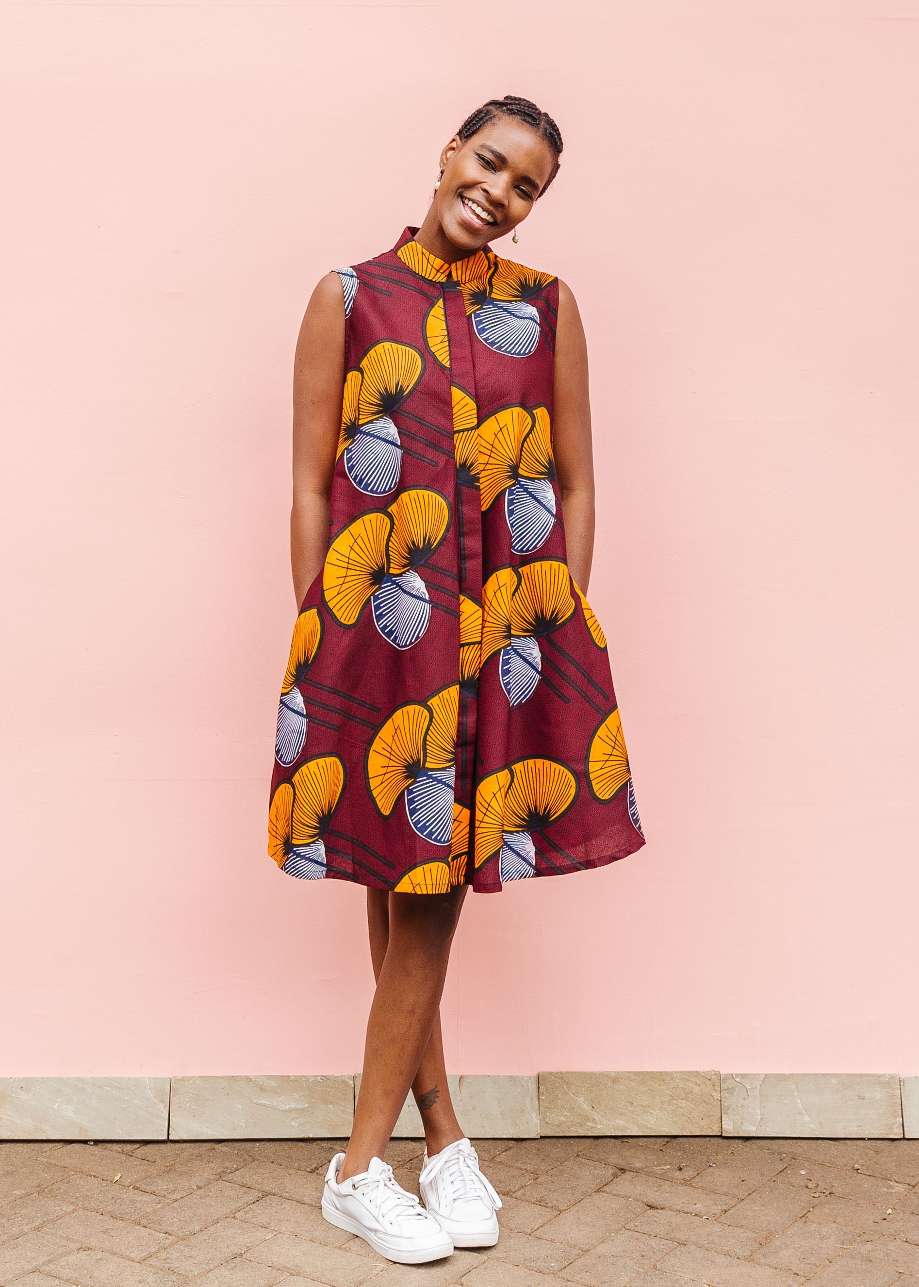 Model wearing burgundy sleeveless dress with yellow and white flowers.