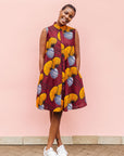 Model wearing burgundy sleeveless dress with yellow and white flowers.